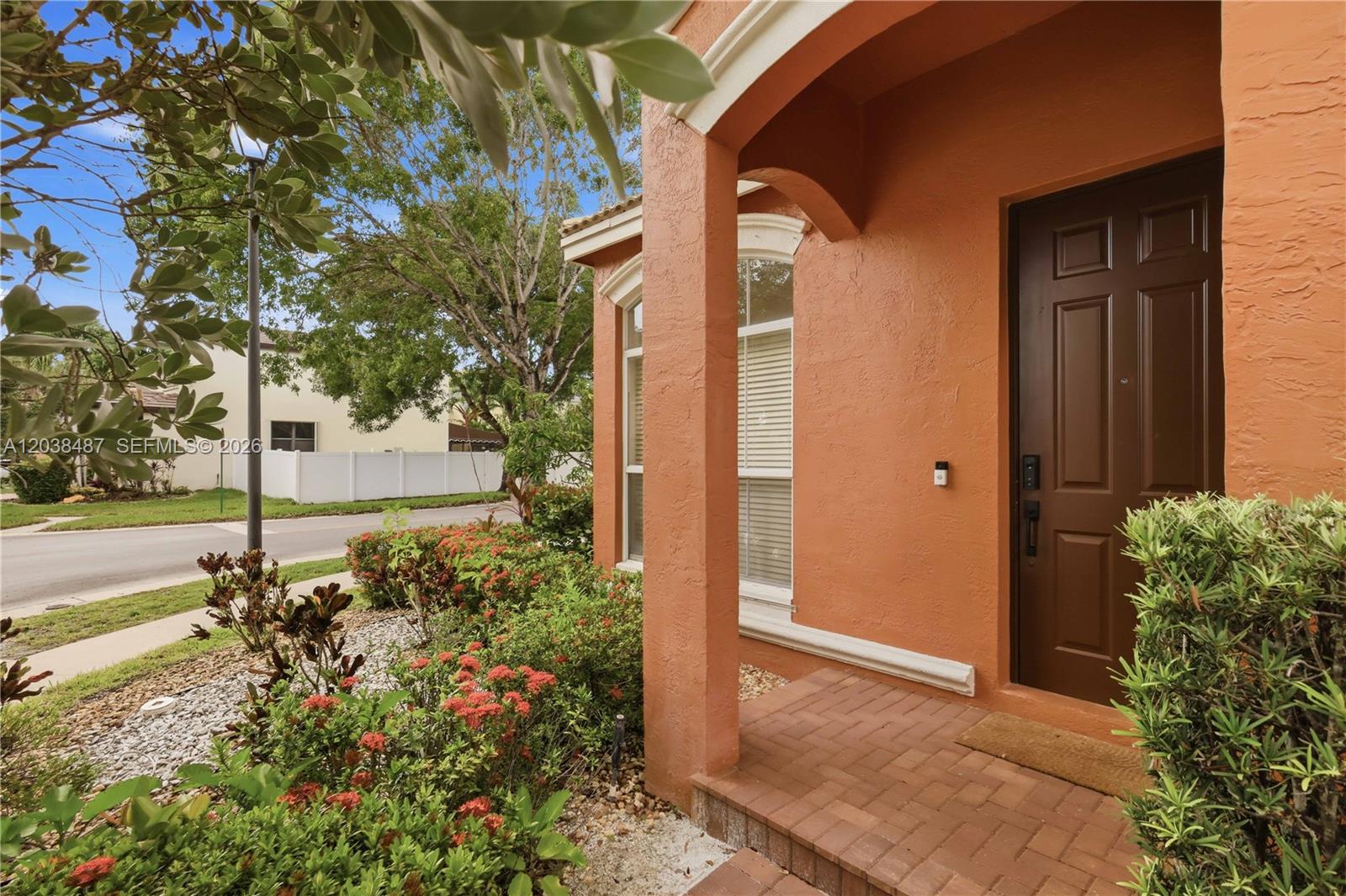 An orange stucco house exterior features a brown front door and a brick porch — 4813 SW 155th Ter, Miramar FL 33027, MIRAMAR, FL
