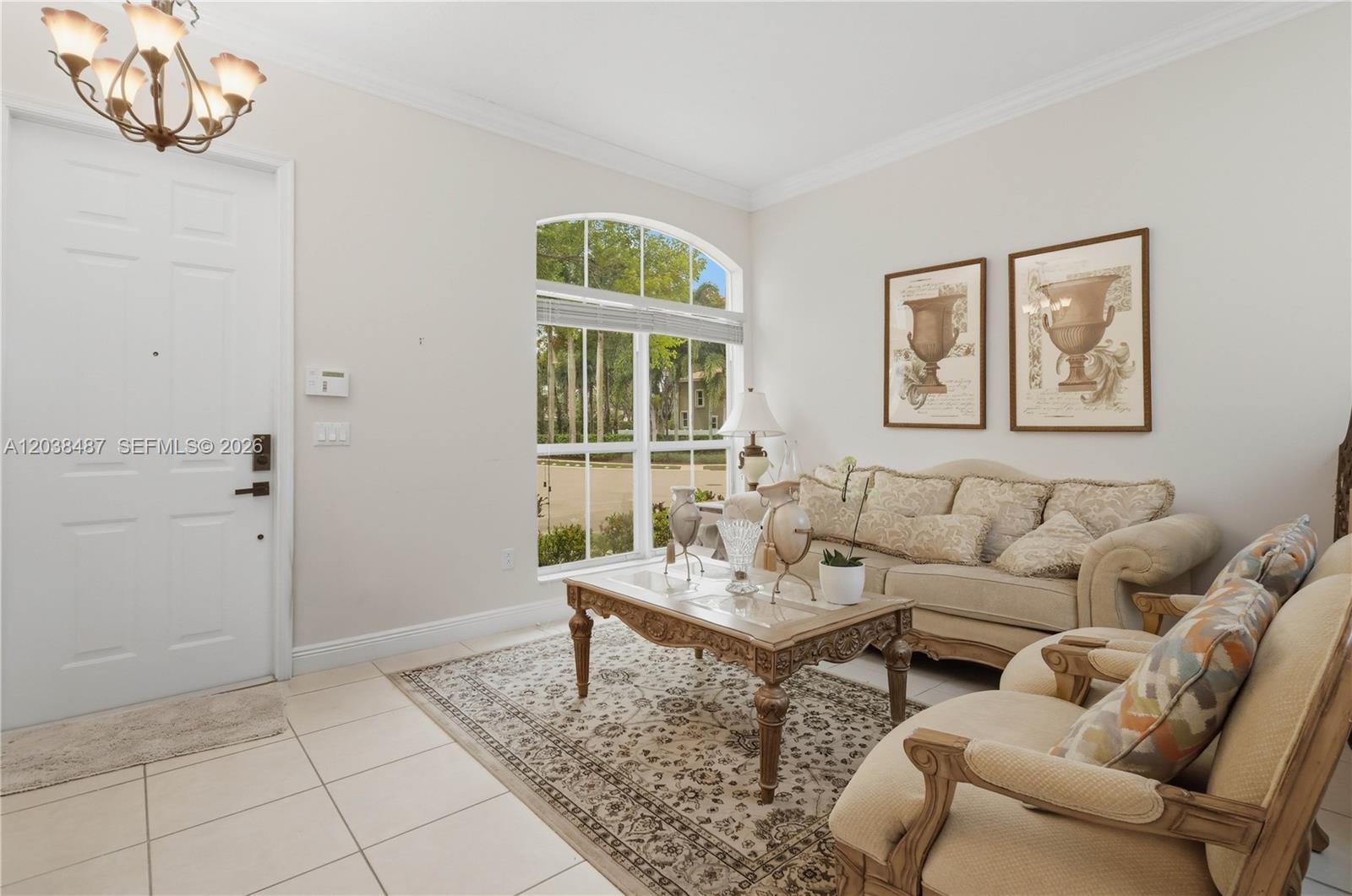 A living room features a beige sofa, patterned rug, arched window, and tiled flooring — 4813 SW 155th Ter, Miramar FL 33027, MIRAMAR, FL