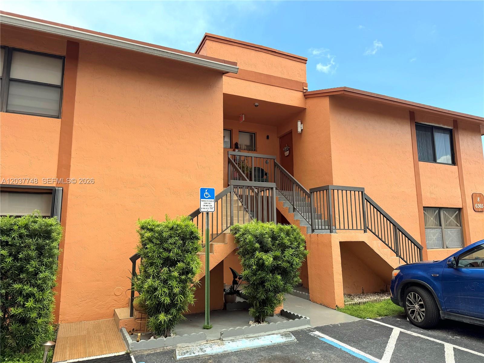 An exterior view of a two-story orange apartment building with an outdoor staircase — 6365 W 27th Ct # 8, Hialeah FL 33016, HIALEAH, FL