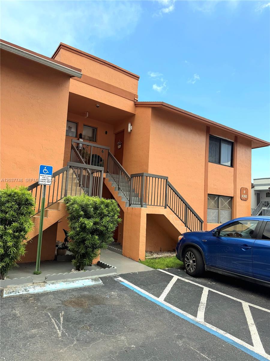 An exterior view of a two-story orange stucco apartment building with an outdoor staircase — 6365 W 27th Ct # 8, Hialeah FL 33016, HIALEAH, FL