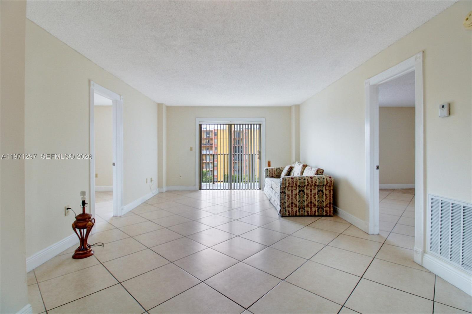 A living room features beige tile floors, a patterned sofa, and a sliding glass door — 4717 NW 7th St # 10, Miami FL 33126, MIAMI, FL
