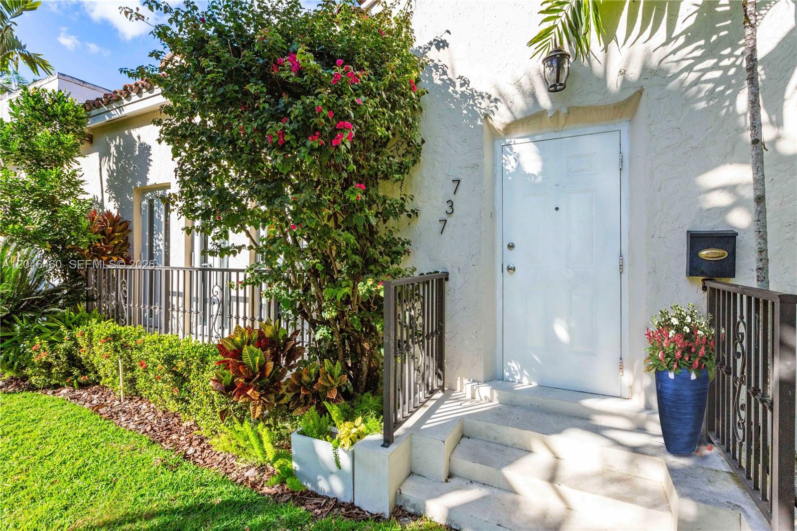 A white front door with house number 737 is framed by a flowering bush and railings — 737 Alhambra Cir, Coral Gables FL 33134, CORAL GABLES, FL