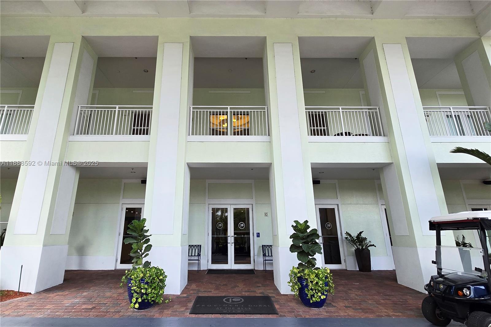 The exterior of a building features a covered entrance with white columns and balconies above — 5300 NW 87th Ave # 1212, Doral FL 33178, DORAL, FL