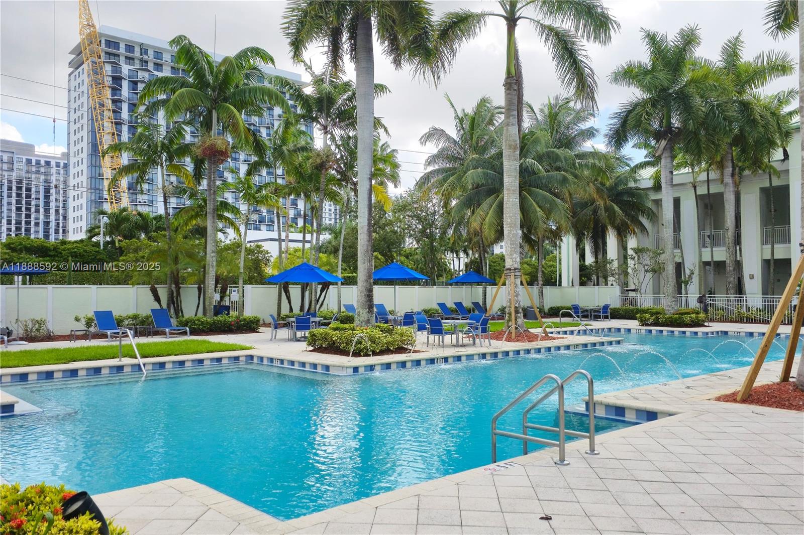 A swimming pool with lounge chairs and umbrellas is surrounded by palm trees and buildings — 5300 NW 87th Ave # 1212, Doral FL 33178, DORAL, FL