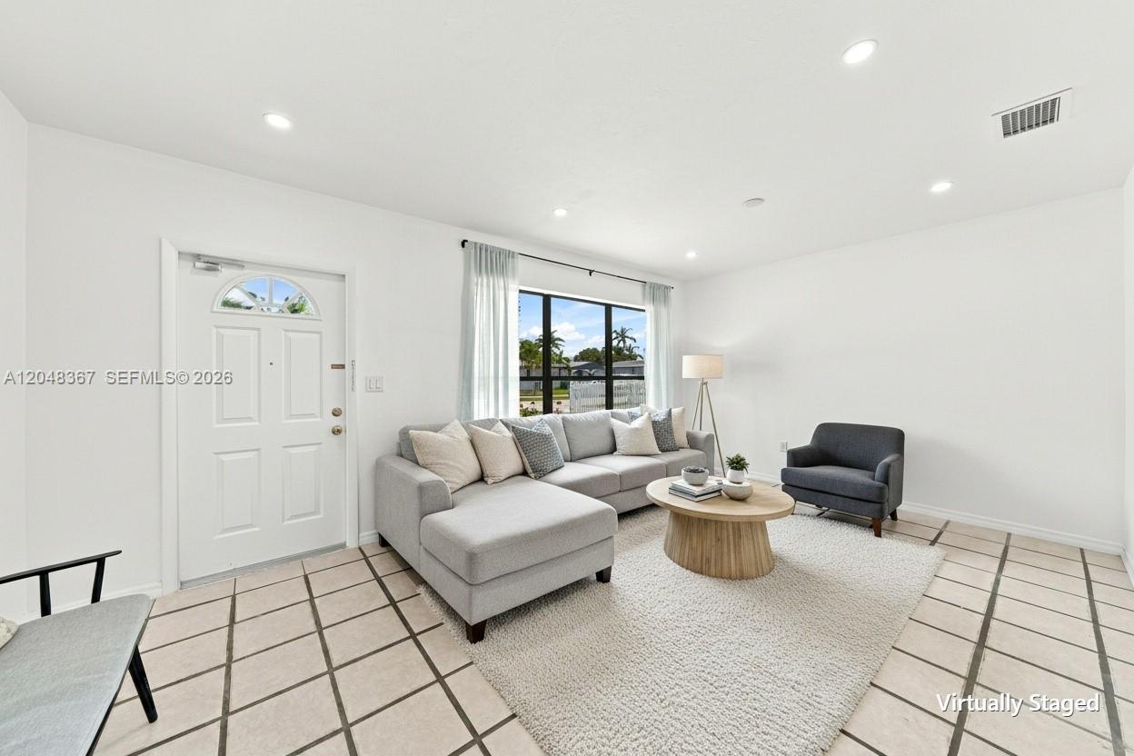 A living room features a gray sectional sofa, a round coffee table, and tile flooring — 14785 SW 297th St, Homestead FL 33033, HOMESTEAD, FL