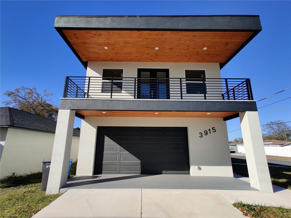 A two-story modern house features a wooden ceiling, a black garage door, and a balcony — 3915 W ROBSON STREET W, TAMPA, FL