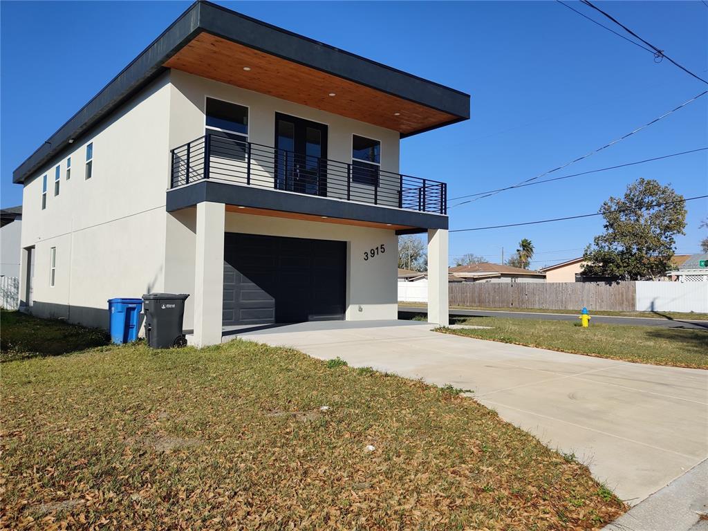 A two-story modern house features a dark garage, a second-floor balcony, and wood-paneled eaves — 3915 W ROBSON STREET W, TAMPA, FL