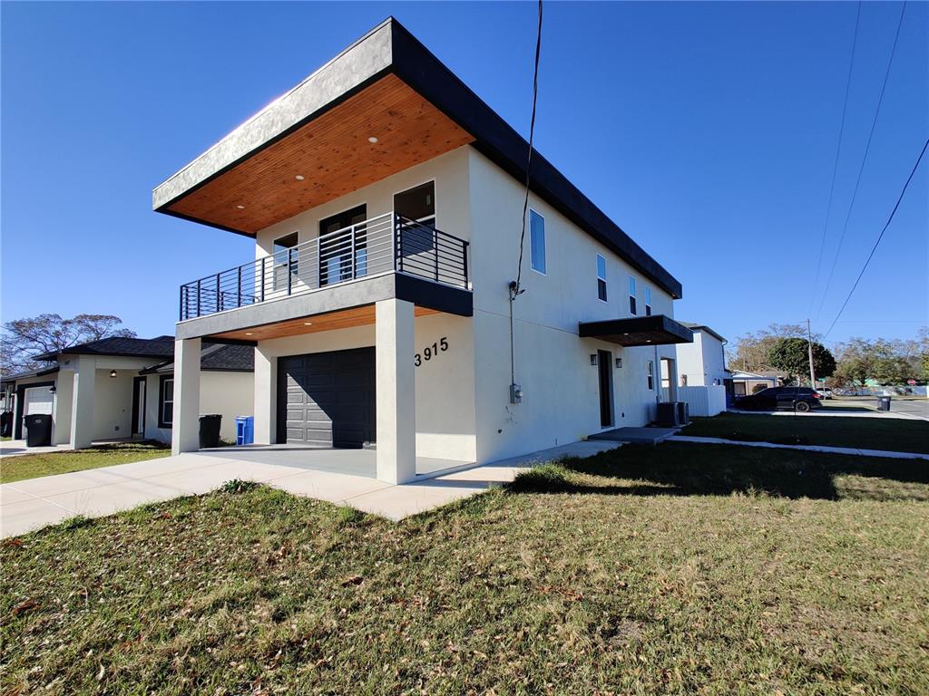 A modern two-story house with a flat roof, wood-paneled overhangs, and a second-floor balcony — 3915 W ROBSON STREET W, TAMPA, FL