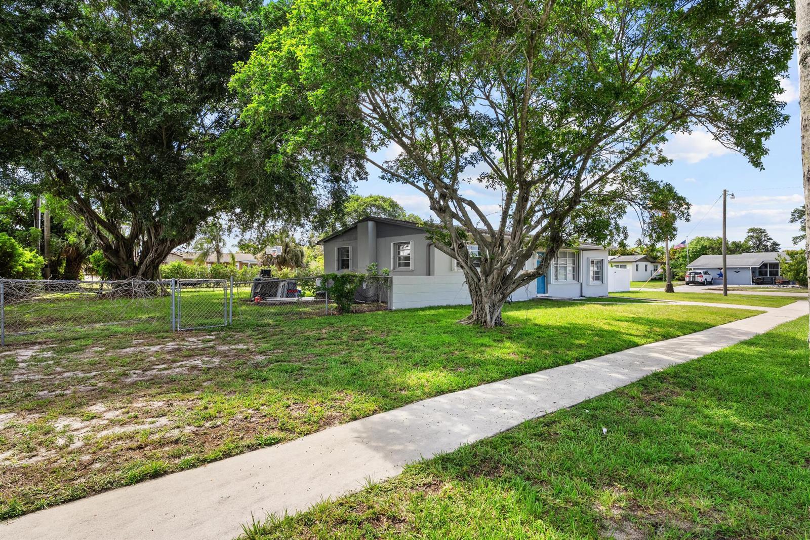 A single-story house with a gray exterior and a large tree in the front yard — 153 Abaco Drive, Palm Springs FL 33461, PALM SPRINGS, FL