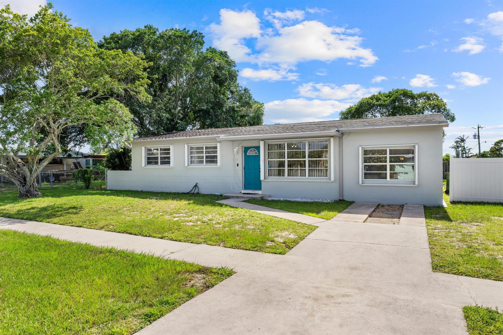 A single-story house with a teal front door, light gray siding, and a concrete driveway — 153 Abaco Drive, Palm Springs FL 33461, PALM SPRINGS, FL
