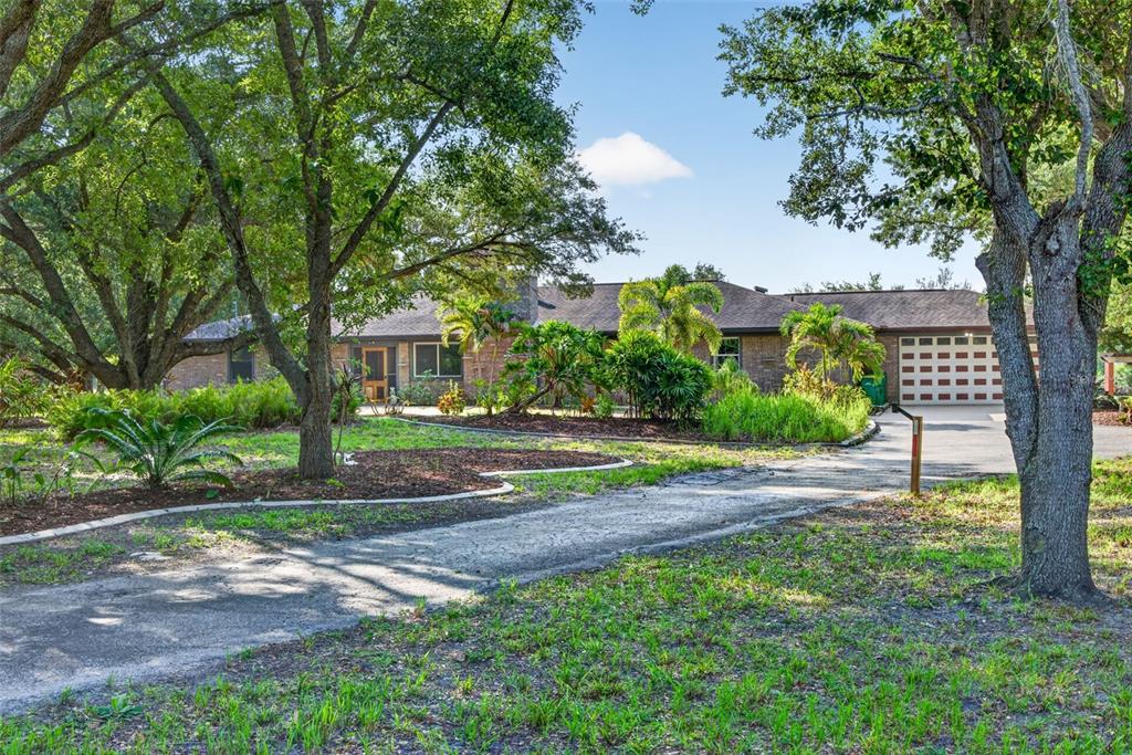 A single-story brick house with a garage and a long driveway surrounded by large trees — 3190 ALOE STREET, PUNTA GORDA, FL