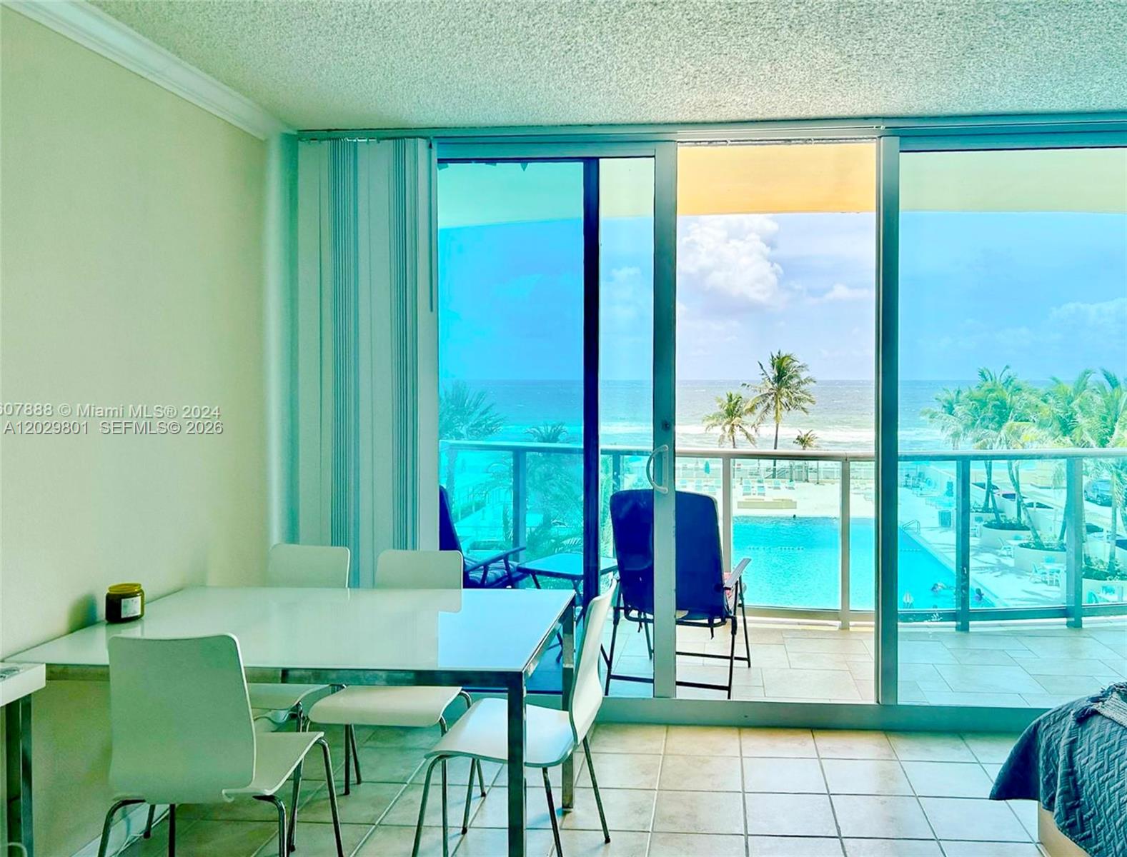 A dining area with a white table and chairs overlooks a balcony, pool, and ocean — 2501 S Ocean Dr # 424, Hollywood FL 33019, HOLLYWOOD, FL