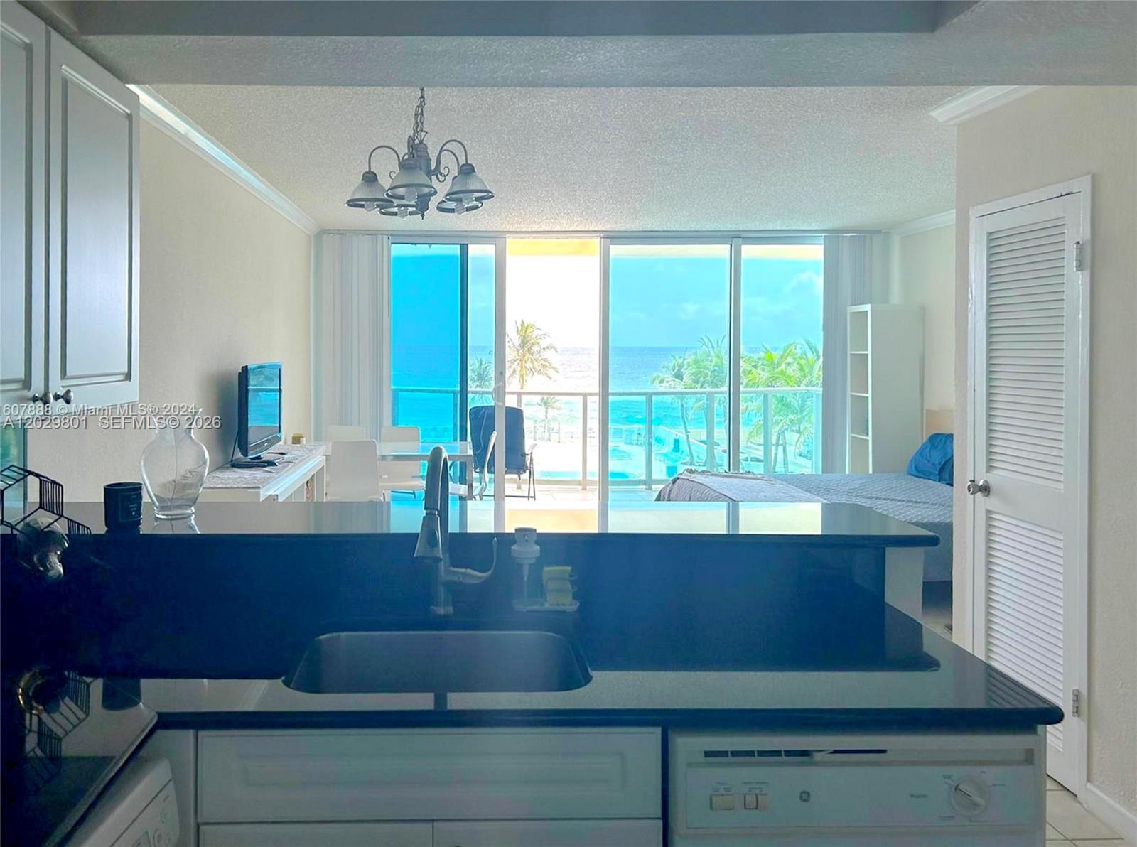 A kitchen with dark countertops overlooks a living area with floor-to-ceiling windows and ocean views — 2501 S Ocean Dr # 424, Hollywood FL 33019, HOLLYWOOD, FL