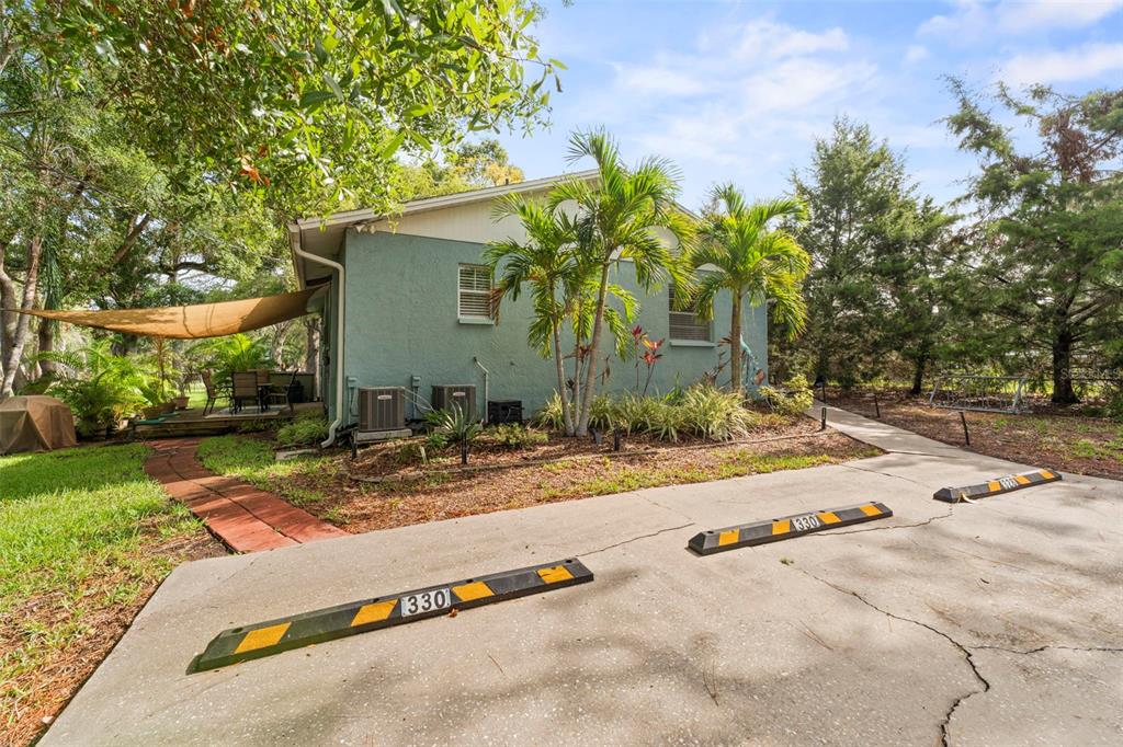 A teal house exterior features a concrete parking area with two numbered wheel stops — 328 PERSHING STREET, DUNEDIN, FL