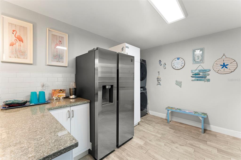 A laundry room features a stainless steel refrigerator, white cabinets, and coastal-themed wall decor — 328 PERSHING STREET, DUNEDIN, FL