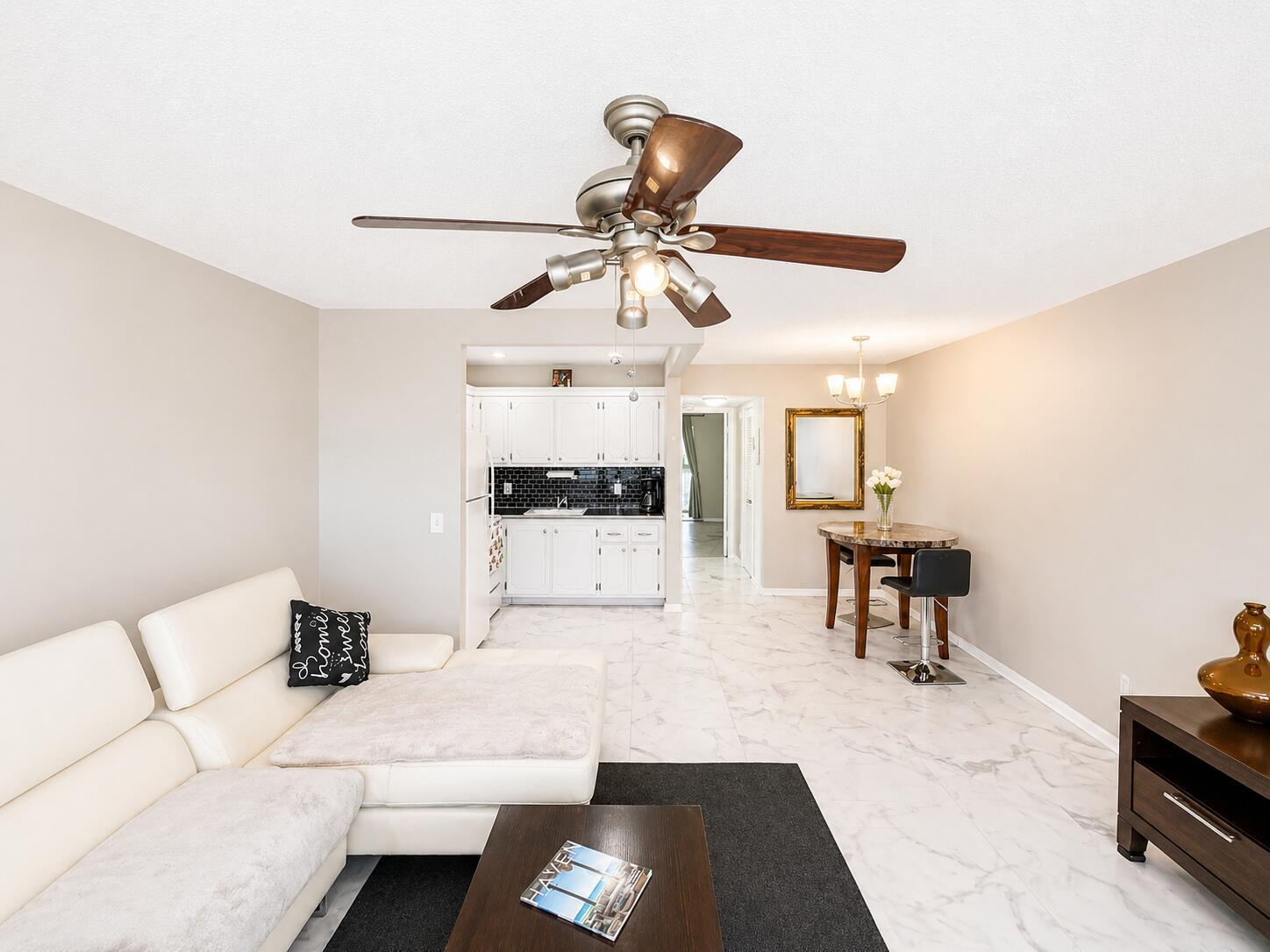 A living room and kitchen area features white tile floors, a ceiling fan, and furniture — 140 Ventnor # I, Deerfield Beach FL 33442, DEERFIELD BEACH, FL