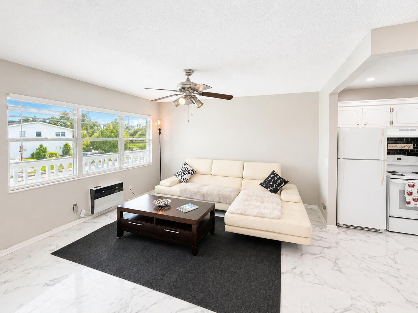 A living room with a white sectional sofa, dark coffee table, and marble-look tile flooring — 140 Ventnor # I, Deerfield Beach FL 33442, DEERFIELD BEACH, FL