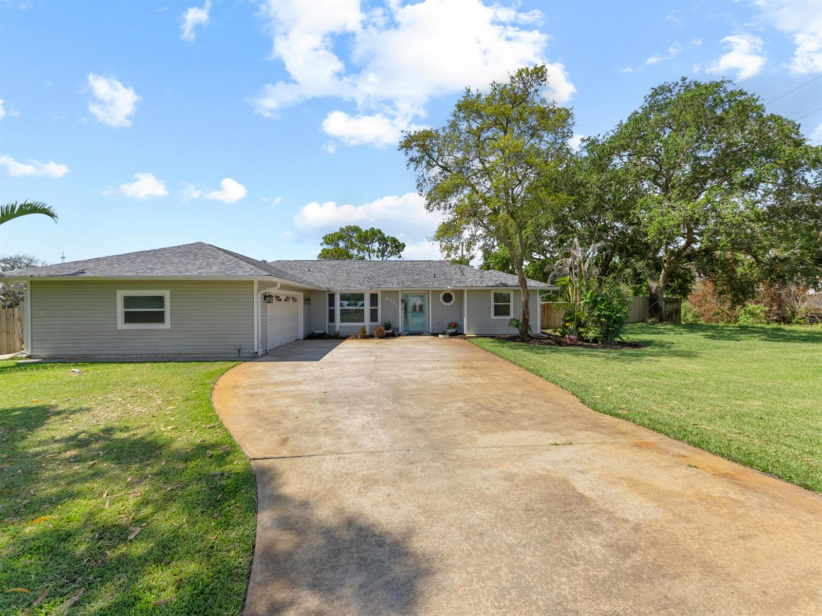 A single-story house with light gray siding, a concrete driveway, and a large front yard — 698 Fischer Drive, Sebastian FL 32958, SEBASTIAN, FL
