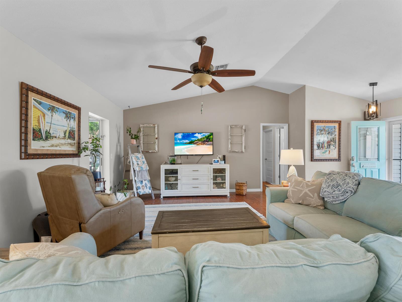 A living room features a vaulted ceiling, a ceiling fan, a television, and light-colored furniture — 698 Fischer Drive, Sebastian FL 32958, SEBASTIAN, FL