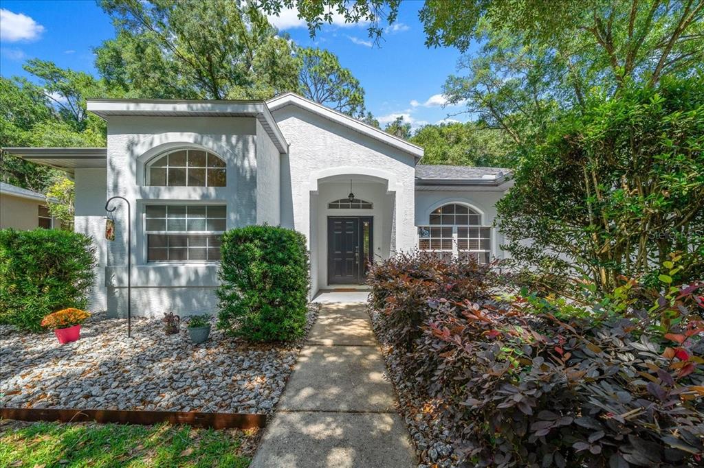 A white stucco house with a dark front door and a concrete walkway — 8859 SW 196TH AVENUE ROAD, DUNNELLON, FL