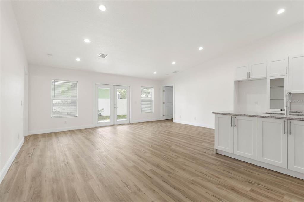 A bright, open-concept living area with light wood-look flooring, white cabinets, and glass patio doors — 28 WOODSTON LANE, PALM COAST, FL