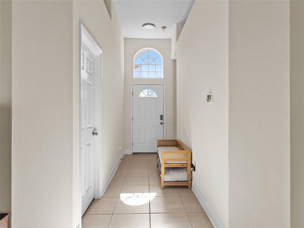 A bright entryway features tiled floors, a white front door, and a wooden bench — 13235 PALMILLA CIRCLE, DADE CITY, FL