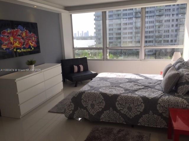 A bedroom with a white dresser, a bed, a black chair, and large floor-to-ceiling windows — 1500 Bay Rd # 758S, Miami Beach FL 33139, MIAMI BEACH, FL