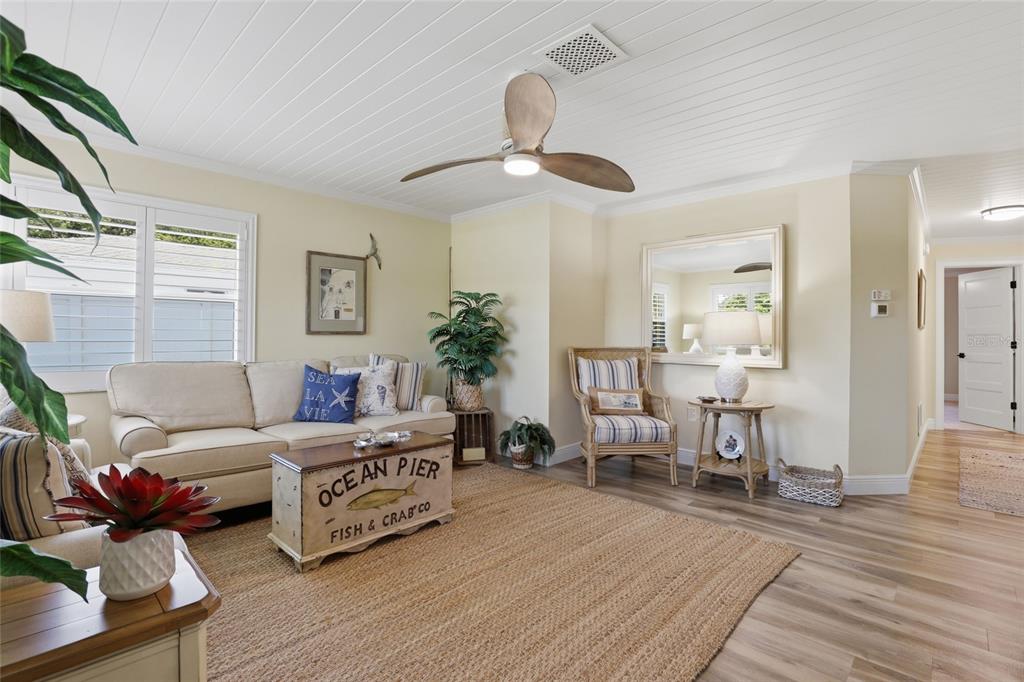 A coastal-style living room features a beige sofa, a wooden coffee table, and wood flooring — 707 BEVERLY ROAD, VENICE, FL