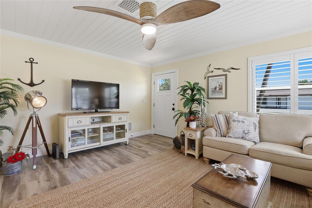 A coastal-themed living room features a ceiling fan, a television console, and a beige sofa — 707 BEVERLY ROAD, VENICE, FL