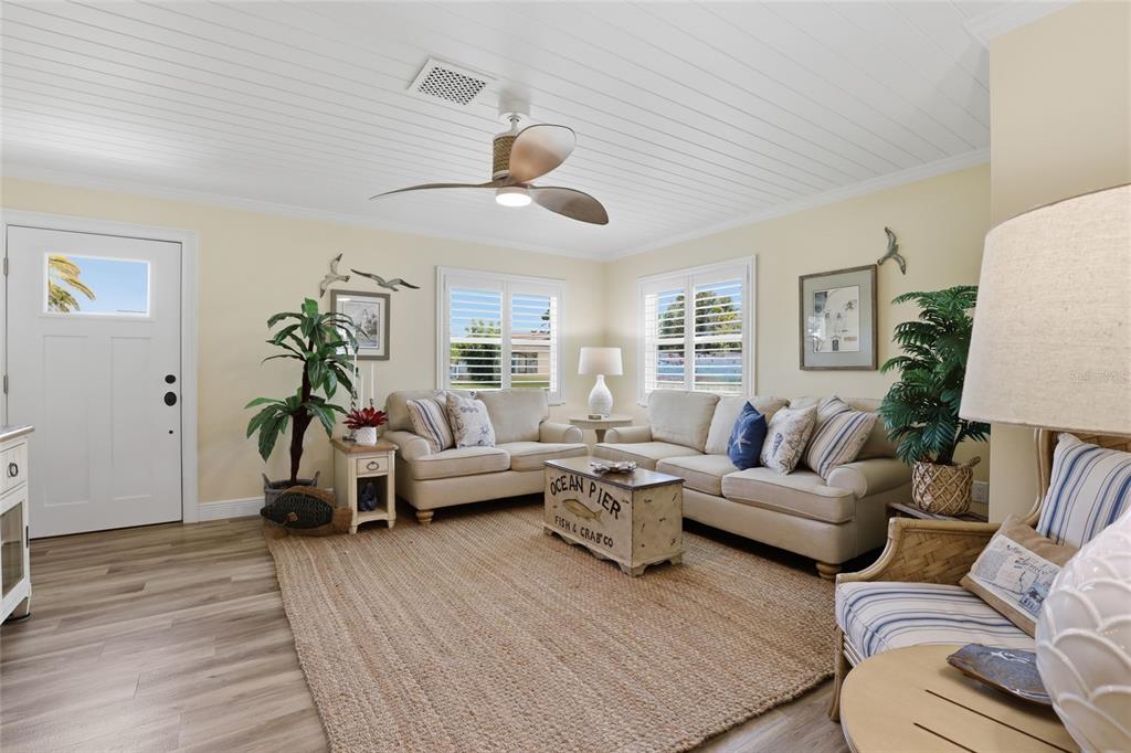 A coastal-style living room features light walls, wood-look flooring, and a white plank ceiling — 707 BEVERLY ROAD, VENICE, FL