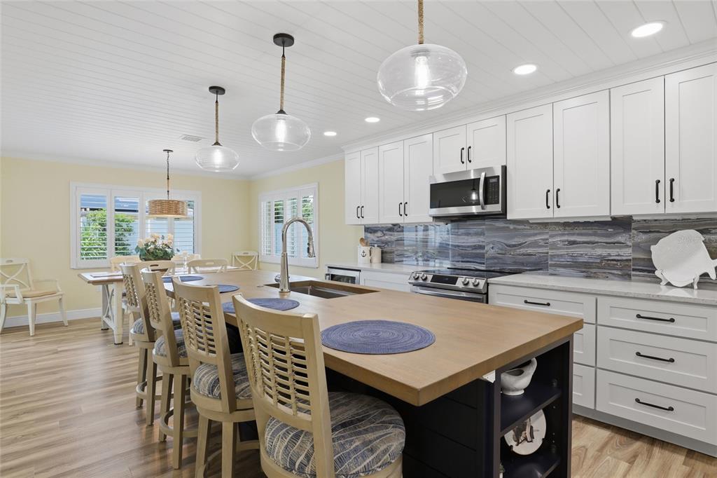A kitchen features white cabinets, a wood-topped island, and a dark blue stone backsplash — 707 BEVERLY ROAD, VENICE, FL