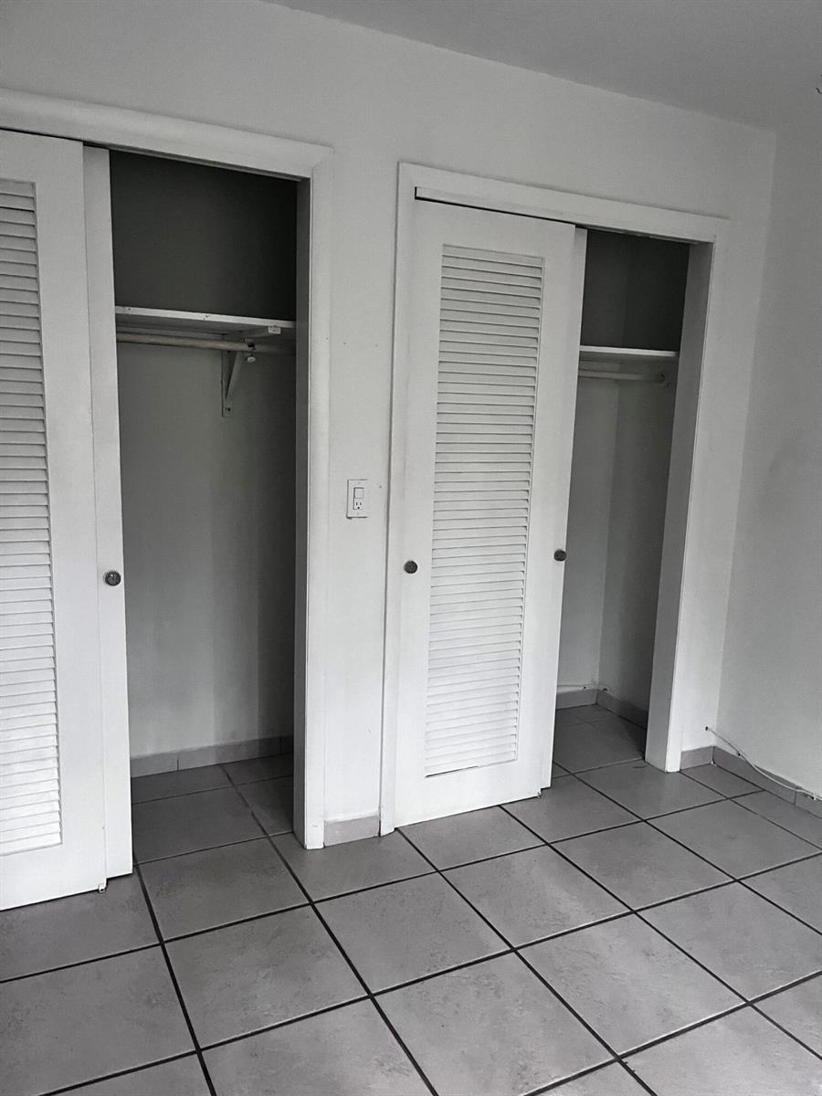 Two white louvered-door closets with interior shelving and hanging rods in a tiled room — 4209 S Olive Avenue, West Palm Beach FL 33405, WEST PALM BEACH, FL