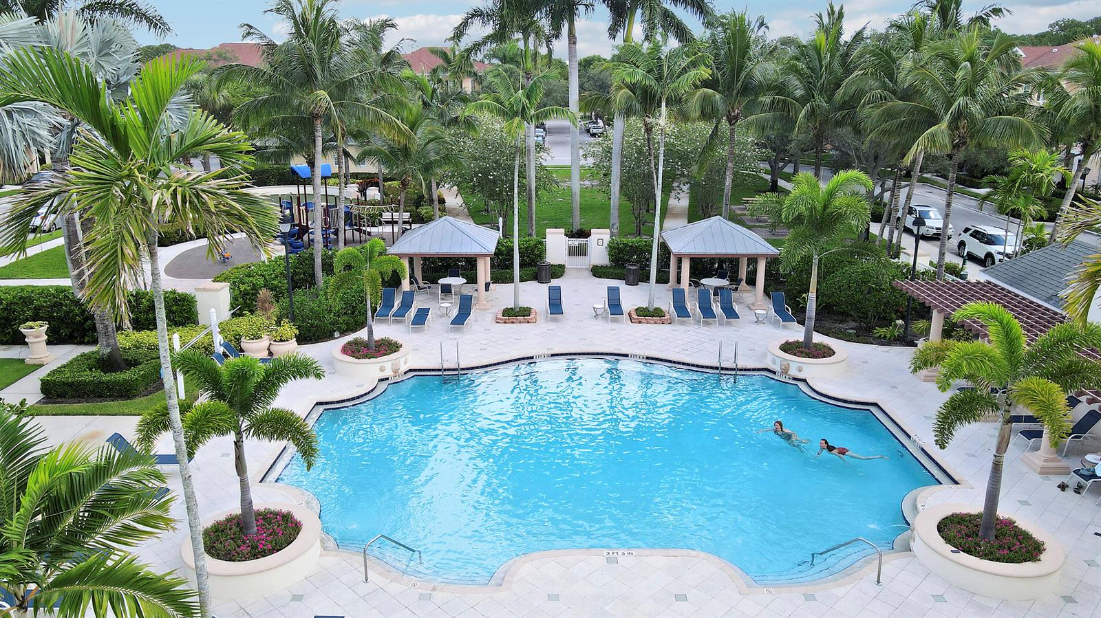 An aerial view of a swimming pool surrounded by palm trees, lounge chairs, and gazebos — 155 Galicia Way # 204, Jupiter FL 33458, JUPITER, FL