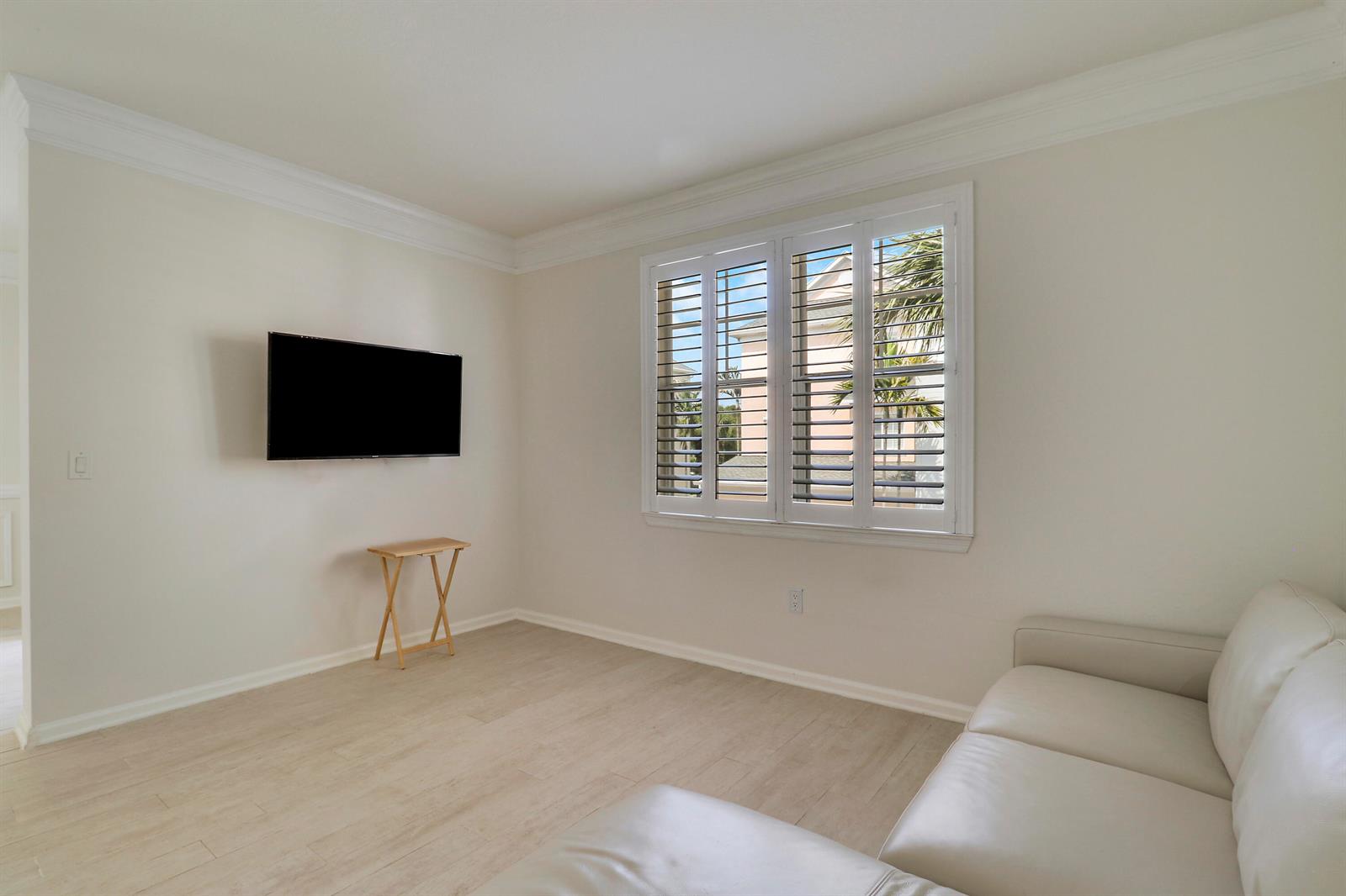 A living room features a wall-mounted television, a small wooden table, and a white sofa — 155 Galicia Way # 204, Jupiter FL 33458, JUPITER, FL