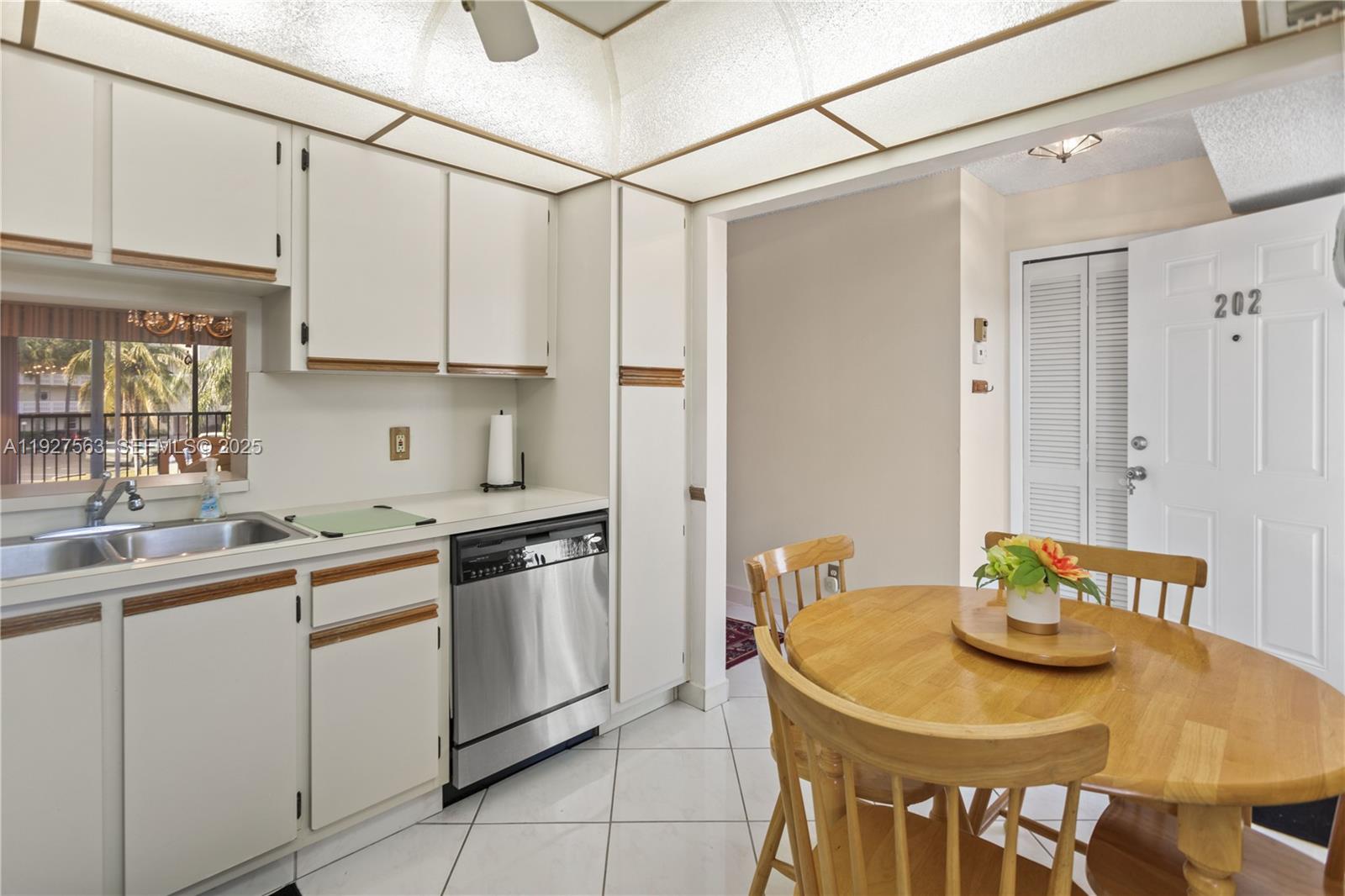 A kitchen with white cabinets, a stainless steel dishwasher, and a wooden dining table — 190 SE 5th Ave # 202, Dania Beach FL 33004, DANIA BEACH, FL