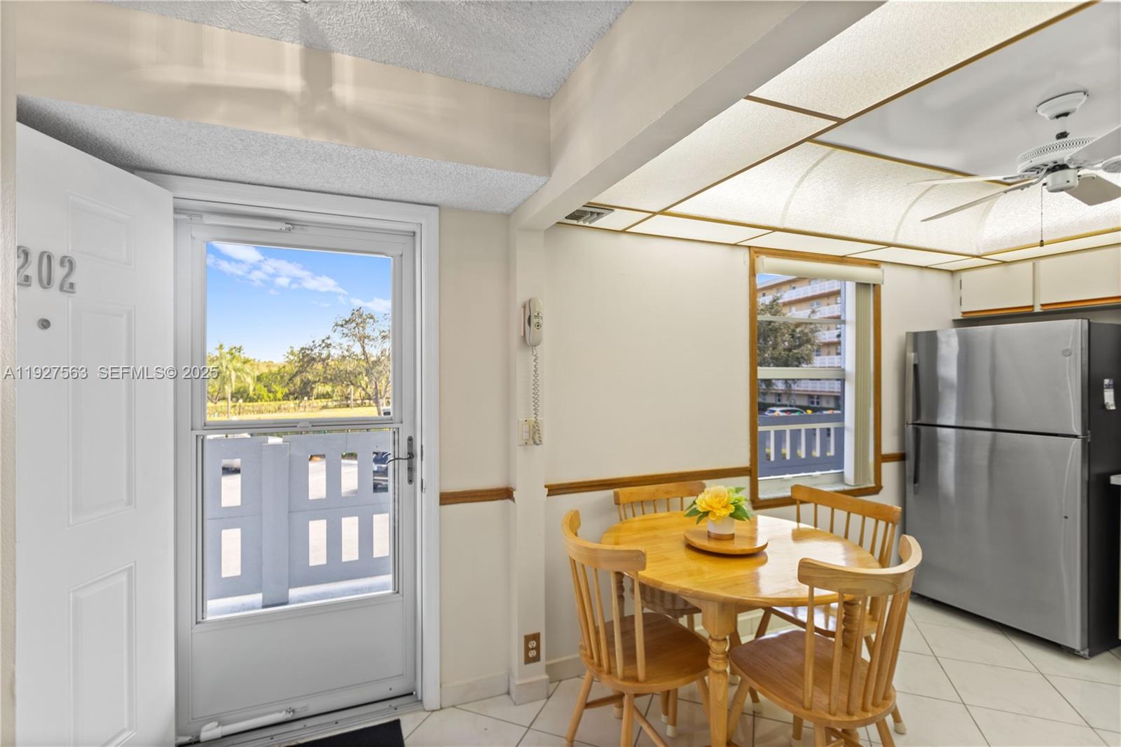 A dining area features a wooden table, four chairs, a stainless refrigerator, and a door — 190 SE 5th Ave # 202, Dania Beach FL 33004, DANIA BEACH, FL