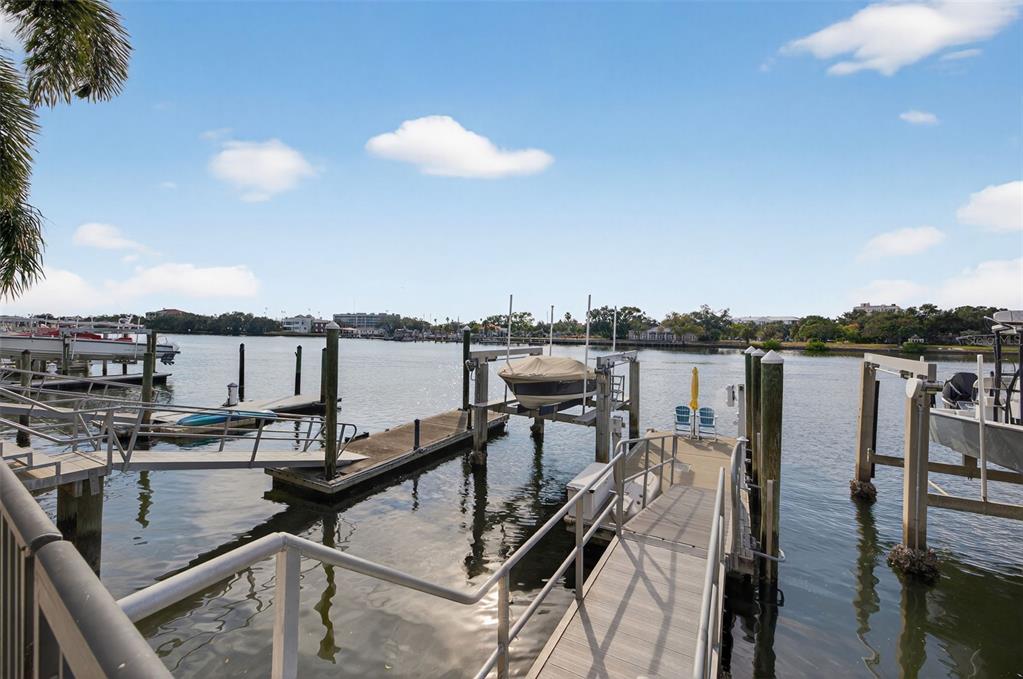 A wooden boat dock with a boat lift extends into a calm waterway under blue skies — 1009 ROYAL PASS ROAD, TAMPA, FL