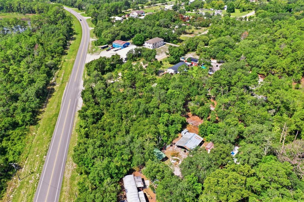 An aerial view shows a road running alongside a wooded area with several buildings — STATE ROAD 44, EUSTIS, FL