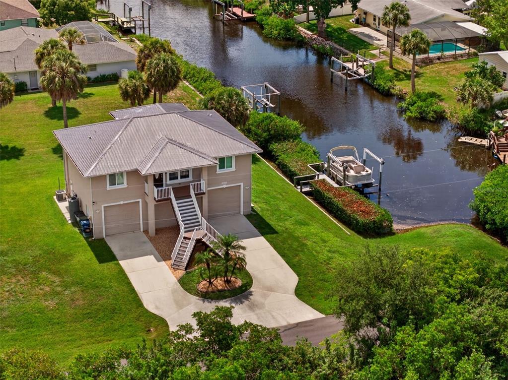 An elevated house with a metal roof and a boat dock on a canal — 9050 CALOOSA DRIVE, VENICE, FL