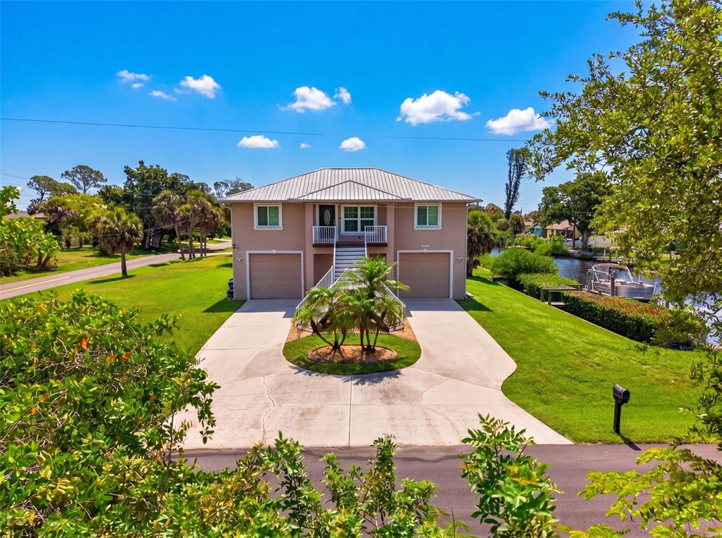 A two-story house with a metal roof, two garage doors, and a central staircase — 9050 CALOOSA DRIVE, VENICE, FL