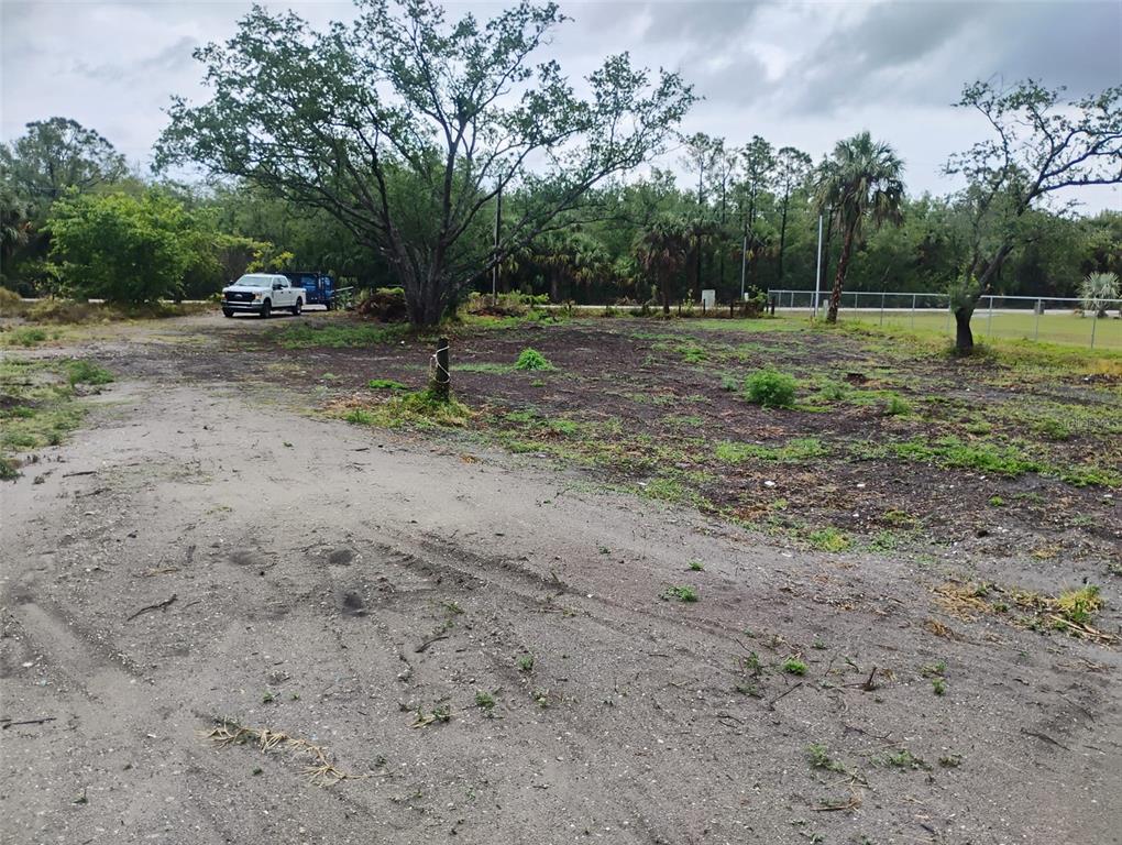 A dirt lot with a large tree, a parked truck, and a chain-link fence — 5905 CLEVELAND DRIVE, PUNTA GORDA, FL