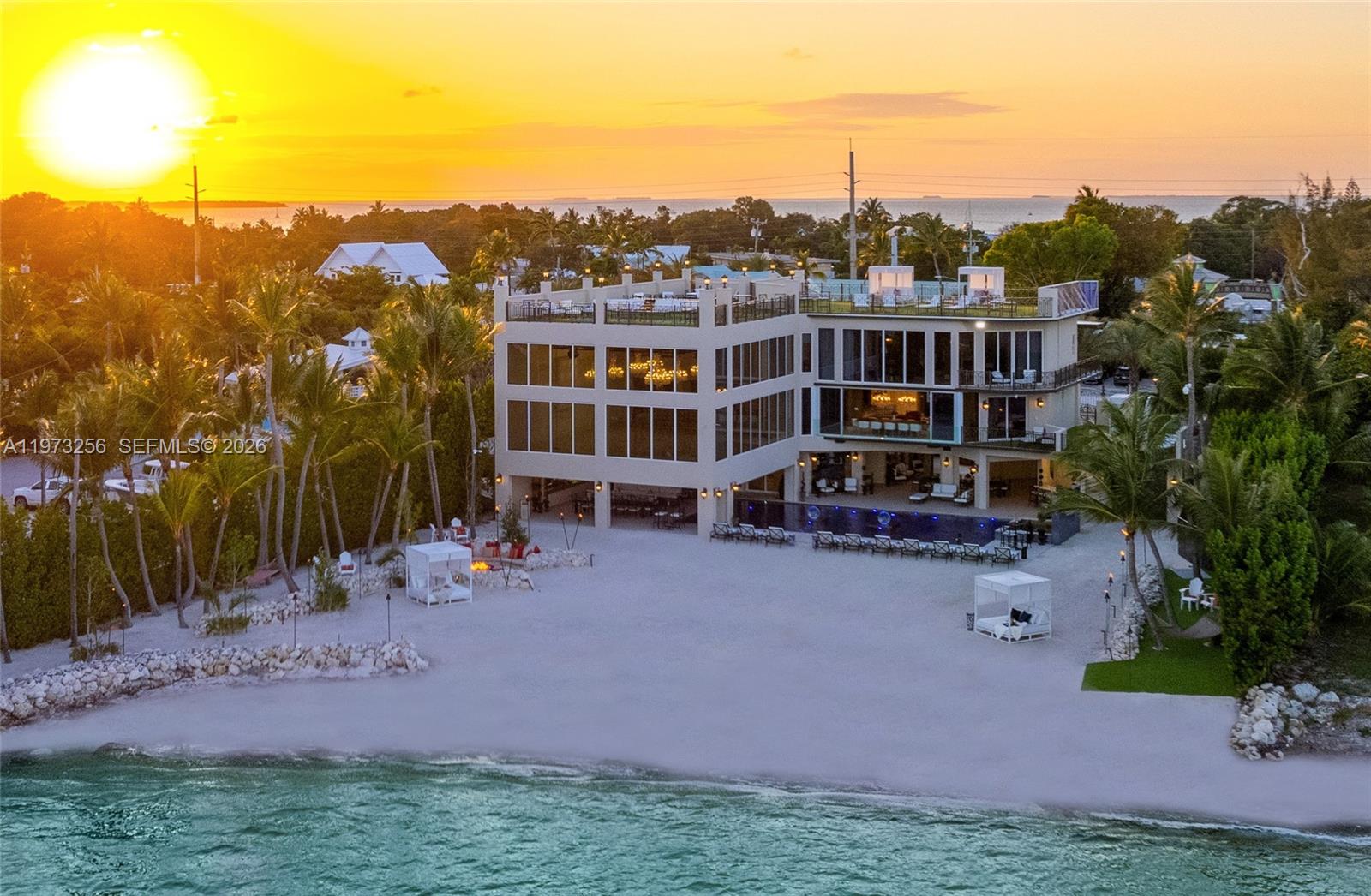 An aerial view shows a modern multi-story beachfront villa with a pool and sandy yard — 82719 Old Hwy, Islamorada FL 33036, ISLAMORADA, FL