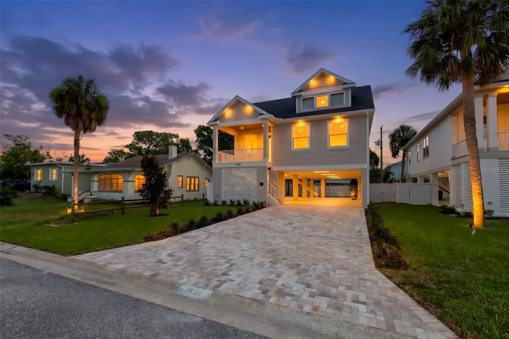A two-story elevated house with a paved driveway and palm trees at dusk — 1868 MISSISSIPPI AVENUE NE, ST PETERSBURG, FL