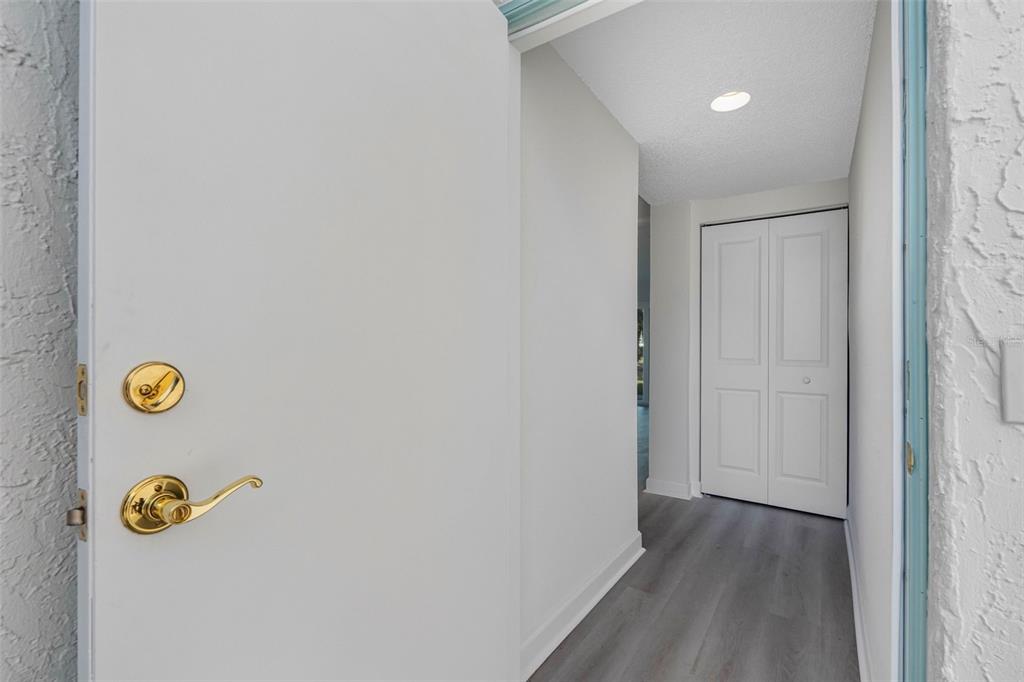 A view through an open door into a hallway with gray flooring and white doors — 1451 GULF BOULEVARD UNIT 101, CLEARWATER BEACH, FL
