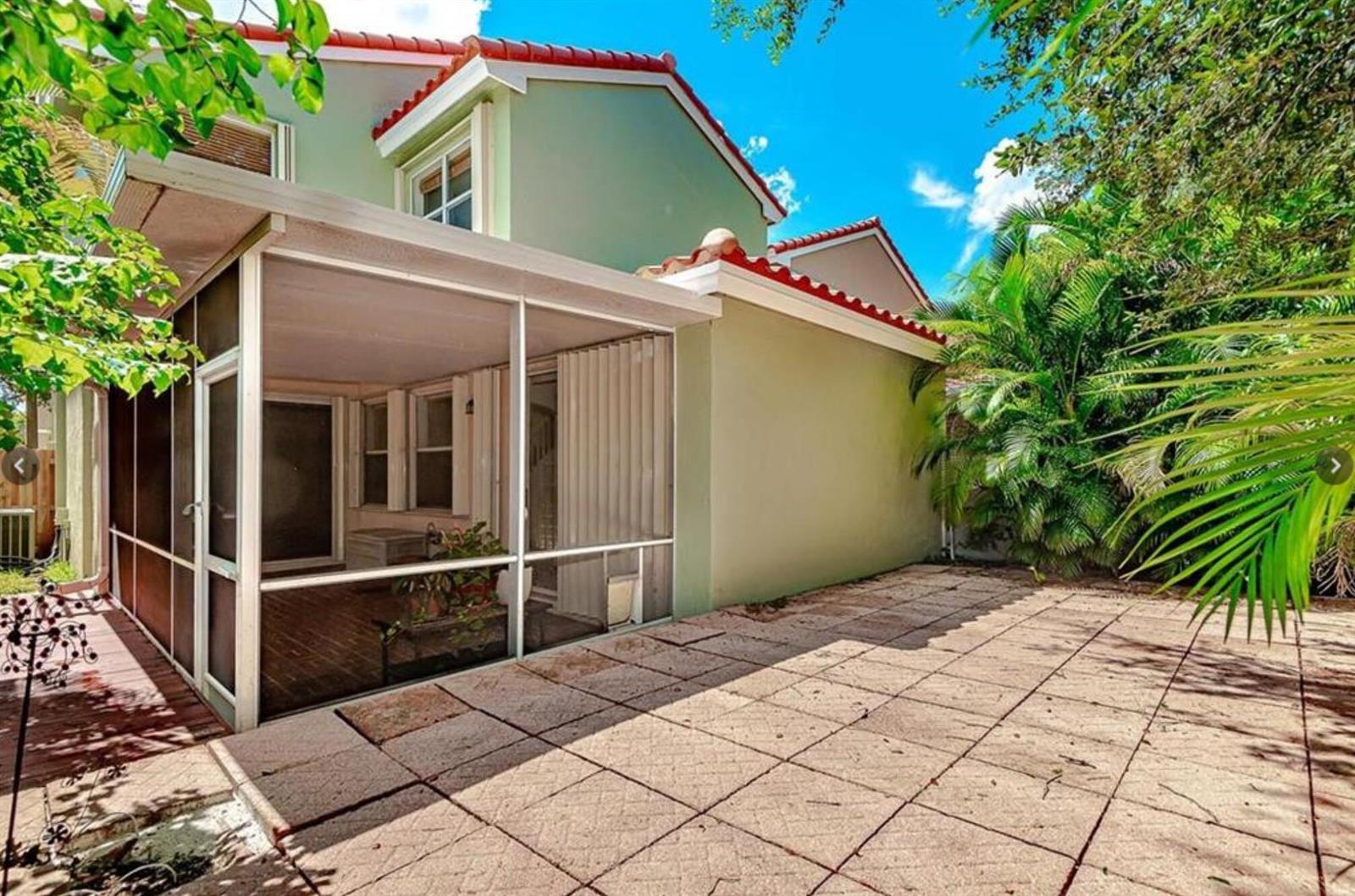 A screened-in porch sits beside a paved patio area next to a two-story house — 4025 Tree Tops Road, Cooper City FL 33026, COOPER CITY, FL