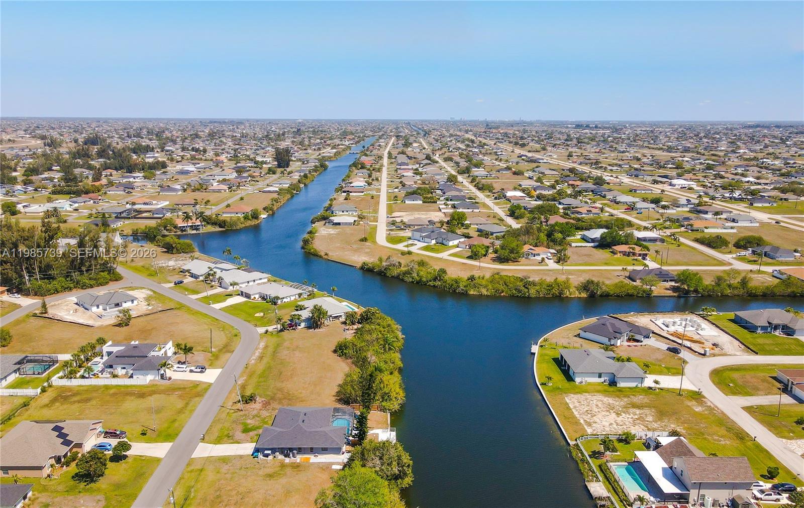 An aerial view shows suburban houses situated along a canal in a residential neighborhood — 2908 NW 9TH TER, Cape Coral FL 33993, CAPE CORAL, FL