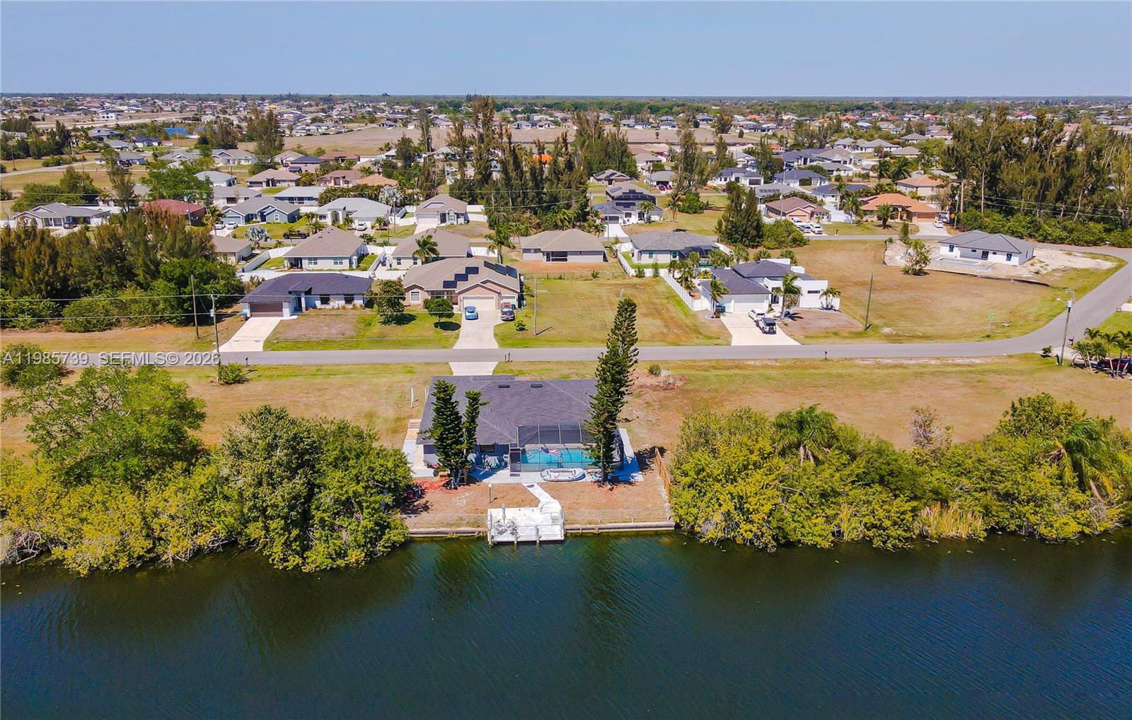 An aerial view shows a waterfront house with a pool, dock, and surrounding residential neighborhood — 2908 NW 9TH TER, Cape Coral FL 33993, CAPE CORAL, FL