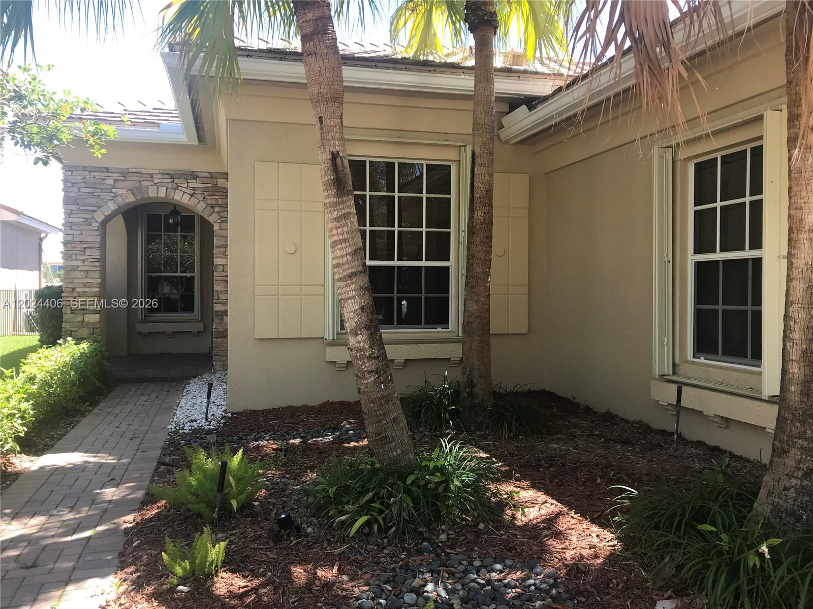 A beige stucco house exterior features stone accents, palm trees, and windows with shutters — 12400 NW 78th Mnr # 0, Parkland FL 33076, PARKLAND, FL