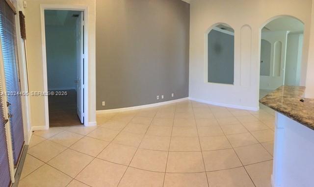 A room with beige tile flooring, a gray accent wall, and arched wall cutouts — 12400 NW 78th Mnr # 0, Parkland FL 33076, PARKLAND, FL