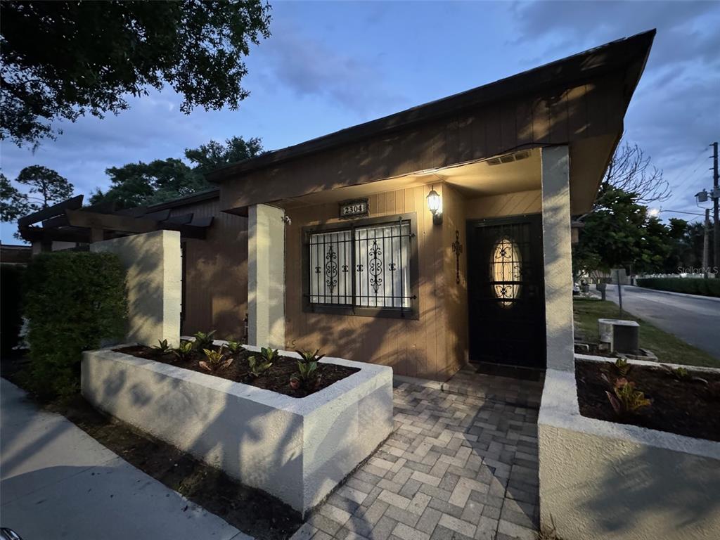 A single-story house exterior features a paved walkway, concrete planters, and a dark front door — 2304 INAGUA WAY UNIT 2304, WINTER PARK, FL